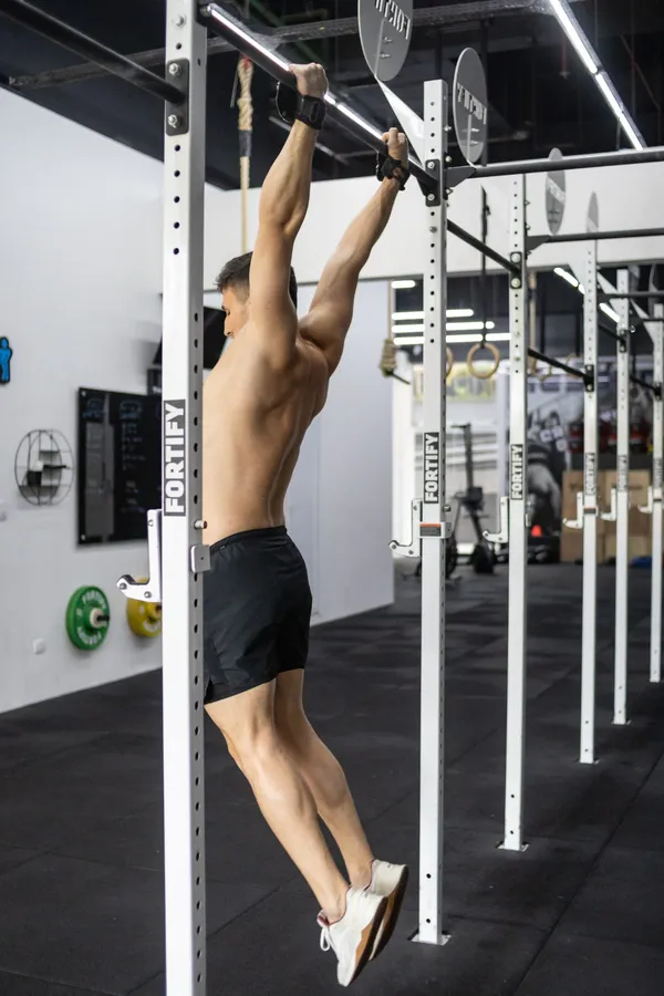 Atleta pendurado na barra fixa